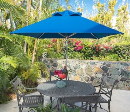 A Frankford blue Greenwich Aluminum Square Market Umbrella shades a small table and chairs at a home in St. John, USVI
