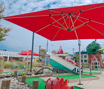 Red Frankford Square Eclipse Cantilever Umbrellas shade a mini golf course in Avalon, New Jersey