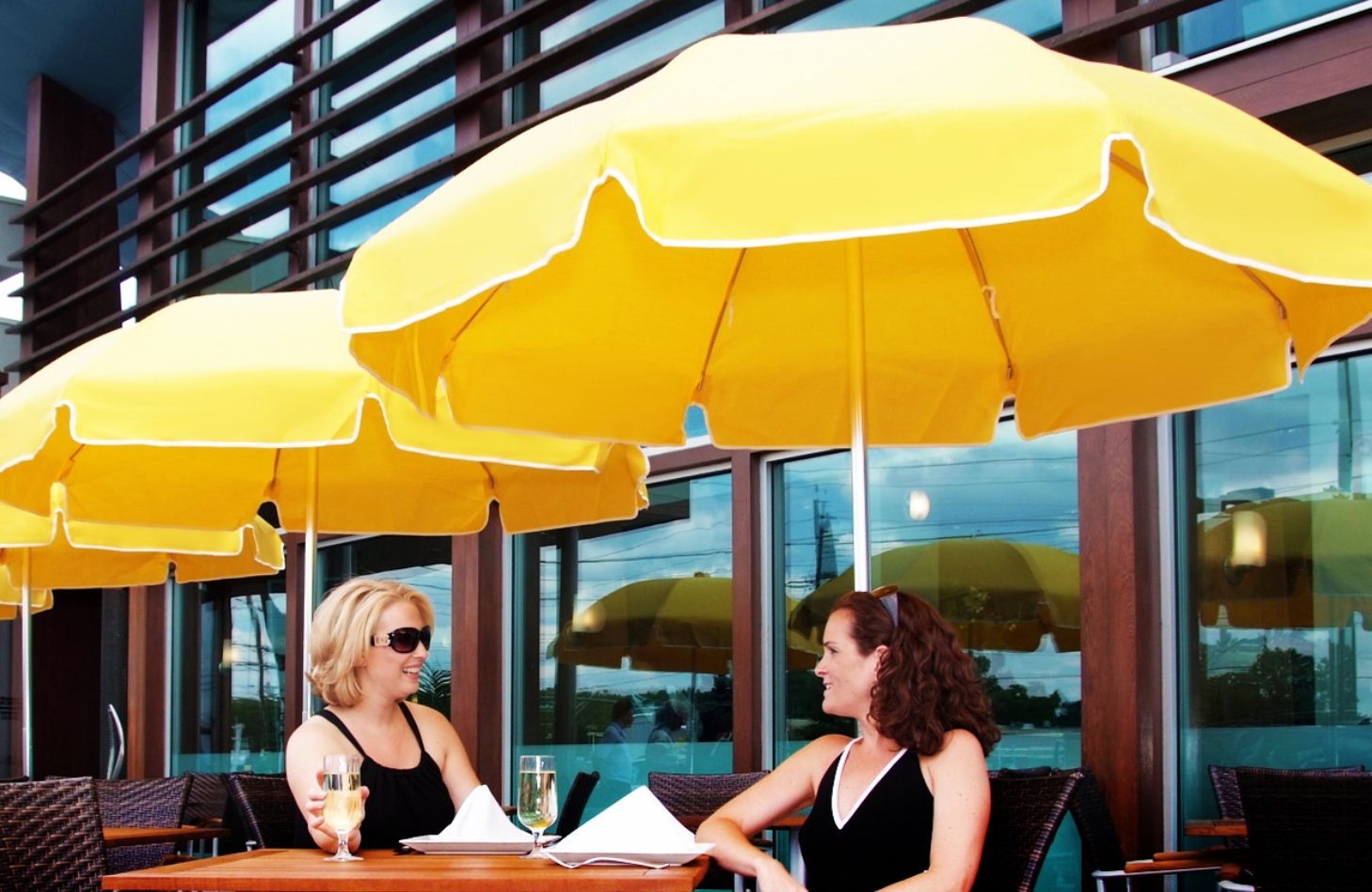 Two women talking under yellow umbrellas